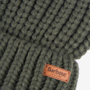 Close-up of a thick, olive green knit fabric with a visible leather patch displaying the brand name "Barbour." The texture is chunky and warm.