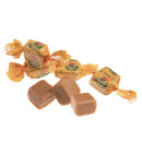 Unwrapped pieces of luxury malt whisky fudge with individually wrapped sweets in gold paper, showing rich creamy texture.