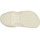 Underside of a bone-coloured Crocs Classic Clog showing textured, non-slip outsole pattern.