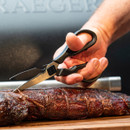 A hand using kitchen shears to cut a piece of perfectly cooked, smoked meat on a cutting board.