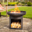 Outdoor metal fire bowl burning with flames, with stacked logs stored in the base.