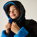 A young girl wearing a black hooded jacket with bright blue fleece lining, gazing upwards with a serene expression. Neutral background. Cosy and warm vibe.