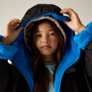 A young girl looks confidently at the camera, adjusting the hood of her black coat with a bright blue, plush lining. She exudes warmth and cosiness.