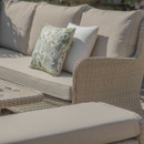 Outdoor wicker sofa with beige cushions and decorative pillows.
