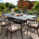 Outdoor dining setup with wine and glasses on a table, surrounded by eight chairs, in a garden setting.