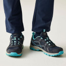 Navy and turquoise walking shoes with lace-up fastening and rugged grip soles, worn with navy outdoor trousers.