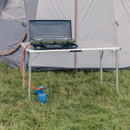 A portable camping table set up outdoors, featuring a camping stove and a blue gas canister, with a tent in the background.