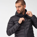 Man in a black puffer jacket with a hood, looking down thoughtfully while adjusting the zipper. The background is a neutral white, conveying a calm tone.