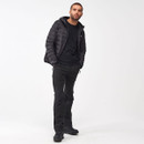 Man in a black puffer jacket and pants stands confidently against a plain white background, hands in pockets, exuding a relaxed and casual vibe.