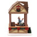 Side view of a Christmas market food stall featuring a vendor, bratwurst, wooden barrels and festive holiday decorations.