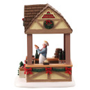 Opposite side view of a festive hut with serving counter, Christmas greenery, red bows and detailed village market accessories.