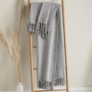A grey and white throw hung up on a blanket ladder