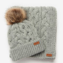 A cosy light gray knit hat with a brown faux fur pom-pom and matching scarf, featuring a cable knit pattern and a small brown label on both.