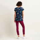 Woman in floral top and maroon pants standing with her back to the camera.