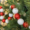 Close-up of a Christmas tree branch adorned with a garland of alternating red and white glittery baubles, creating a festive and cheerful atmosphere.
