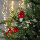 Festive tree branch with a red and white mushroom ornament, red berries, and green leaves, set against soft, warm fairy lights in the background. Festive tree branch with a red and white mushroom ornament, red berries, and green leaves, set against soft, warm fairy lights in the background.