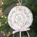 A close up view of a large pastel lollipop pick on a Christmas tree