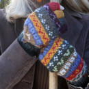 A person wearing colourful, patterned mittens holds a wooden stick. The mittens are striped with various vibrant colours against a dark coat. Cosy, winter scene. A person wearing colourful, patterned mittens holds a wooden stick. The mittens are striped with various vibrant colours against a dark coat. Cosy, winter scene.
