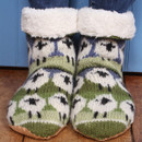 Cosy knitted slipper socks with a sheep pattern, featuring green and white colours and fluffy white cuffs, rest on a wooden floor, conveying warmth and comfort. Cosy knitted slipper socks with a sheep pattern, featuring green and white colours and fluffy white cuffs, rest on a wooden floor, conveying warmth and comfort.