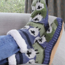 Cosy, multicoloured knit slipper socks with a fun, abstract pattern are worn over jeans. The scene is relaxed, with a soft couch in the background. Cosy, multicoloured knit slipper socks with a fun, abstract pattern are worn over jeans. The scene is relaxed, with a soft couch in the background.