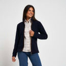 Woman modelling a navy fleece jacket with brown zip trim over a checked shirt and blue jeans.