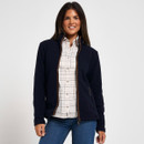 Woman wearing a navy fleece jacket with brown trim over a checked shirt and blue jeans.