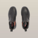 Top view of a pair of black leather pull-on work boots with brown elastic sides, placed side by side on a beige background. Top view of a pair of black leather pull-on work boots with brown elastic sides, placed side by side on a beige background.