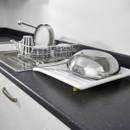 Kitchen sink drainer tray with dish rack and utensils, white plastic draining board for drying plates, bowls and cookware on countertop