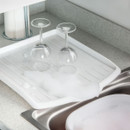 Close-up of white sink drainer tray with ridged design and drainage grooves, compact kitchen drying board for glassware and dishes