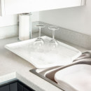 White plastic dish drainer tray with wine glasses drying upside down, kitchen sink accessory with ridged surface for efficient water drain