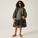 The young child wears an oversized camo coat with orange lining, grey shirt, dark shorts, sunglasses, and orange sandals, conveying a cool, confident vibe.