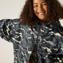 Smiling person with curly hair wearing a black and white camo-patterned jacket. The jacket has "Regatta Great Outdoors" branding. The mood is joyful.