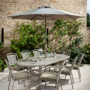 Outdoor patio dining area with table, chairs, and umbrella, against a brick wall with greenery.
