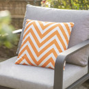 Orange and white chevron-patterned cushion on a grey outdoor chair.