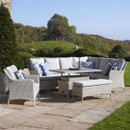 Elegant outdoor seating area featuring a sofa, armchair, dining table and a bench surrounded by lush greenery and blue skies.