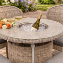 Round rattan bar table with built-in ice bucket holding a wine bottle and glasses, surrounded by cushioned wicker chairs on a patio