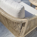 A close-up of a rope-weave outdoor sofa showing the natural rope detailing wrapped around a light wooden frame with soft beige cushions on top.