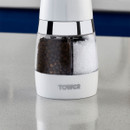 Close-up of Tower electric salt and pepper grinder showing separate transparent chambers filled with peppercorns and salt.