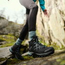 A person wearing black walking boots with blue accents