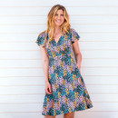 Person in a floral dress standing against a white striped background.