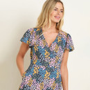 A person wearing a floral dress with a V-neckline, standing against a plain background.