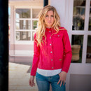 Woman in a red jacket and blue jeans standing outside.