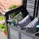 Close-up of the open garden storage bench filled with outdoor cushions and pillows, showing the spacious interior compartment.