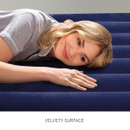 Woman lying on a navy inflatable airbed highlighting the soft, velvety flocked sleeping surface for added comfort.