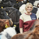 Person in a t-shirt standing amidst a herd of cows.