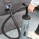 A hand-operated air pump is being used to inflate a grey inflatable chair, with a focus on the pump's hose and handle.