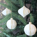 4 white paper decorations in different shapes hanging on a tree