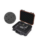 Open black hard case with orange trim, containing cameras and lenses secured in foam padding. Inset shows close-up of cross-cut foam texture.