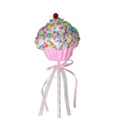 Colourful cupcake decoration with a cherry on top, adorned with sprinkles, resting on a striped stick tied with ribbons.