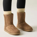 Pair of tan suede mid-calf boots worn with cream knitted socks and black leggings, shown from the front.